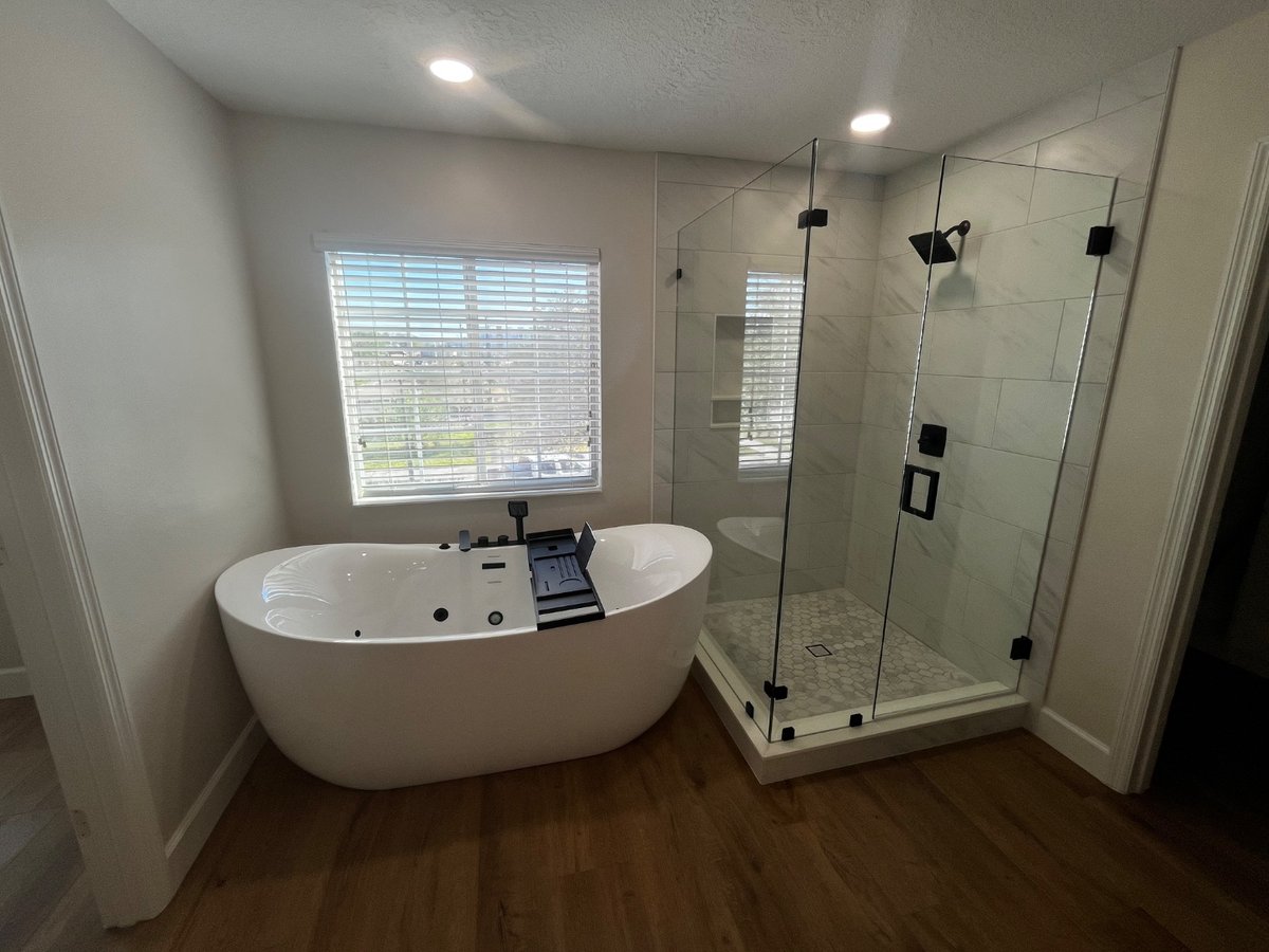 After: luxury bathroom remodel with freestanding tub, glass shower, and marble tile by KV Tileworks