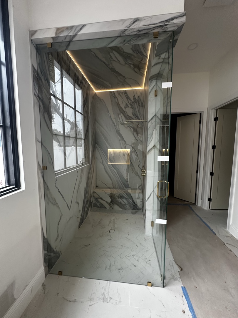 Completed frameless glass shower with LED cove and full-height marble by KV Tileworks