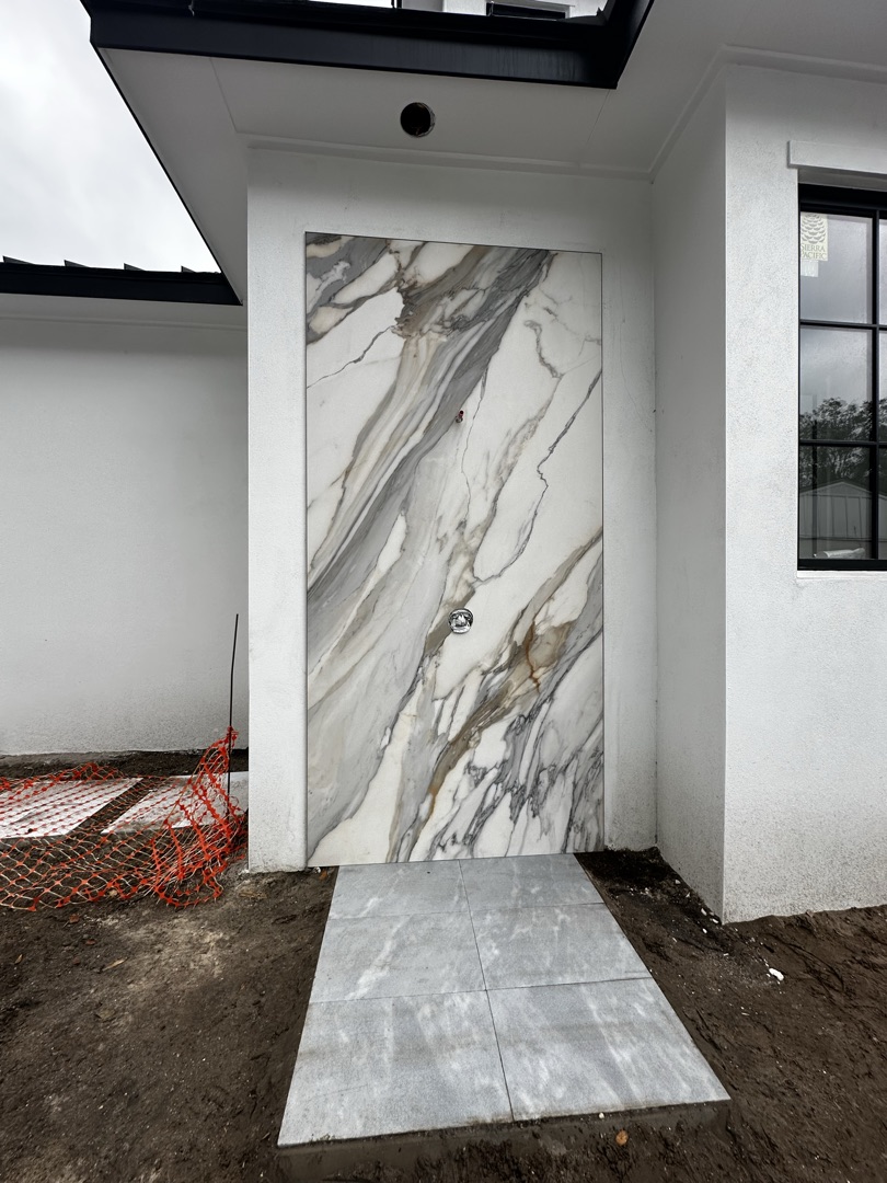 Large slab stone accent wall on front door exterior by KV Tileworks
